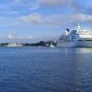 Blick über den Großen Hafen. Im Vordergrund ein Holzsteg mit einem Segelboot. Im Hintergrund am Bontekai ein weißes Kreuzfahrtschiff.